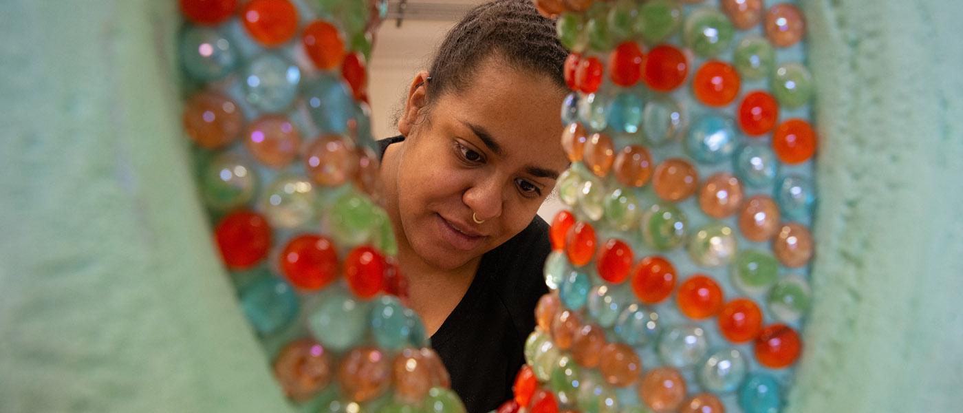 Up close view of a colorful art project with art student working on it in the background