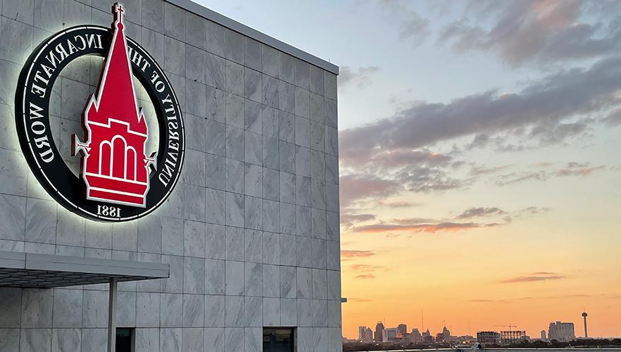 UIW logo on building with San Antonio skyline background